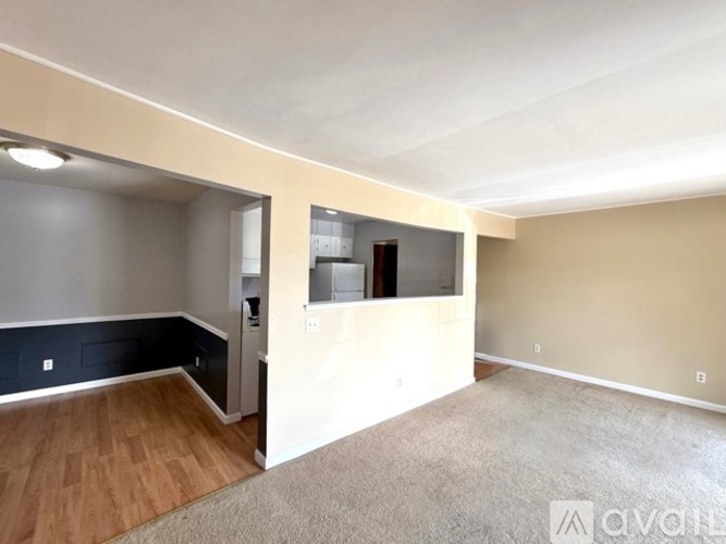 A room with a carpeted floor and a wall-mounted TV.
