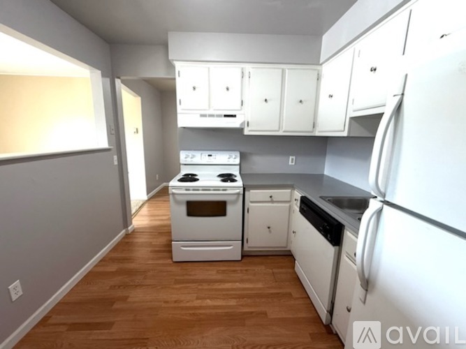 A kitchen with white appliances and wooden floors.