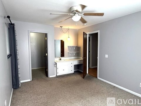 A room with a bed, a desk, and a fan.