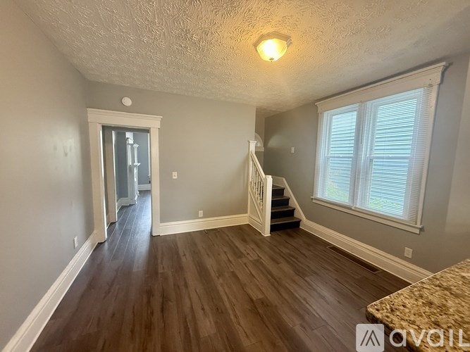 A room with wooden floors and a staircase leading to another room.
