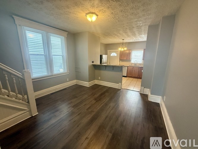 A room with wooden floors and a staircase on the left side.