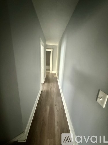 A long hallway with wood floors and white walls.