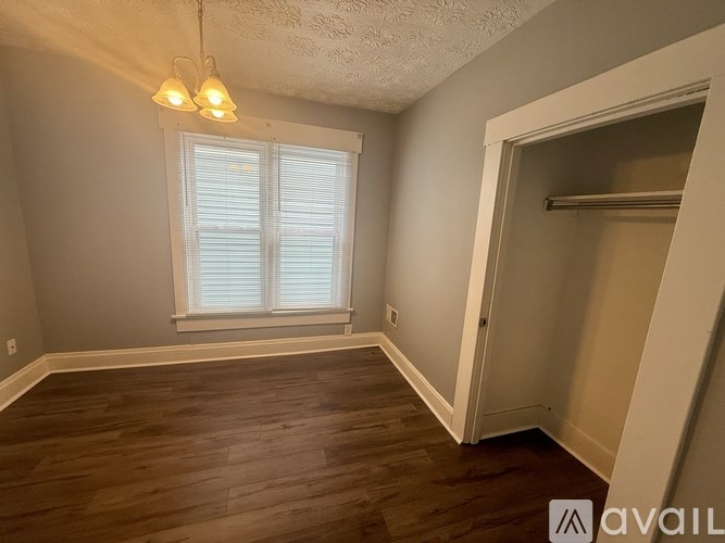 A room with wooden floors and a window with blinds.
