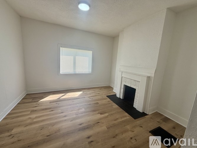 A room with a fireplace and wooden flooring.