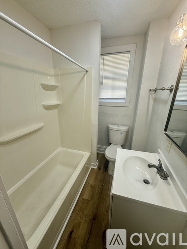 A white bathroom with a toilet, sink, and bathtub.