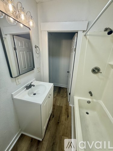 A small bathroom with a white sink and a white bathtub.