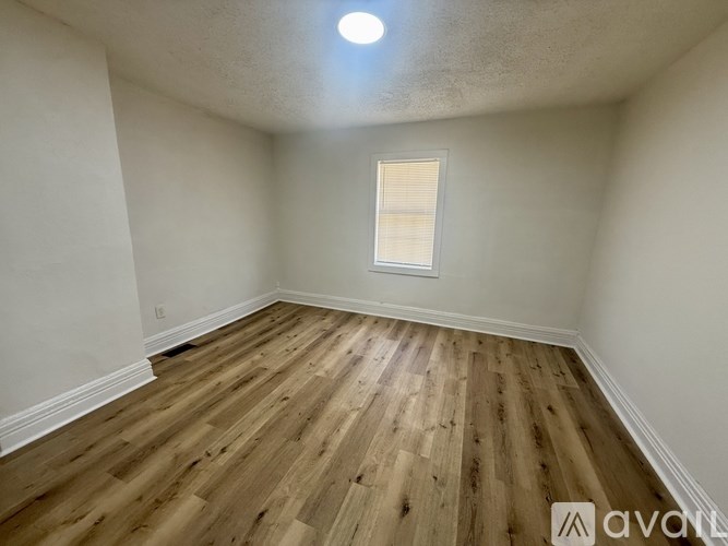 A room with wooden flooring and a window with blinds.