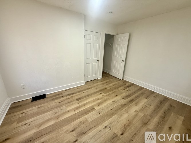 A room with wooden flooring and two white doors.