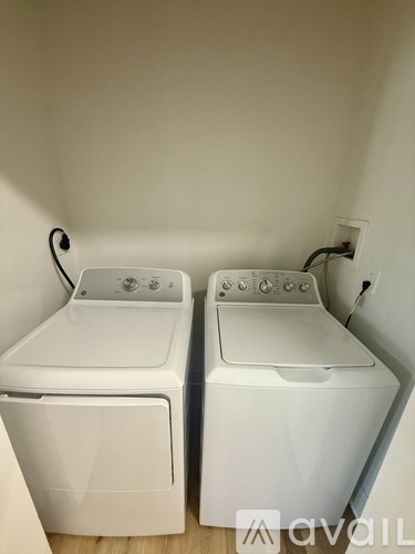 Two white front loading washing machines in a laundry room.