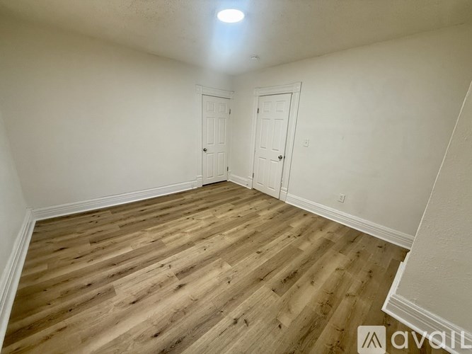 A room with wooden flooring and two white doors.