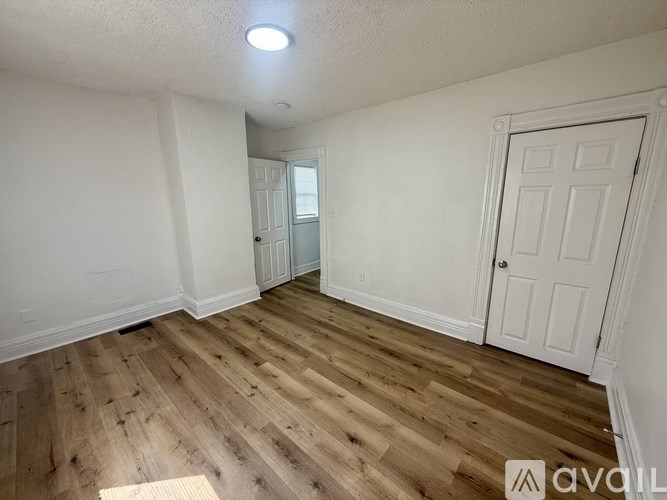 A room with wooden flooring and two doors, one of which is open.