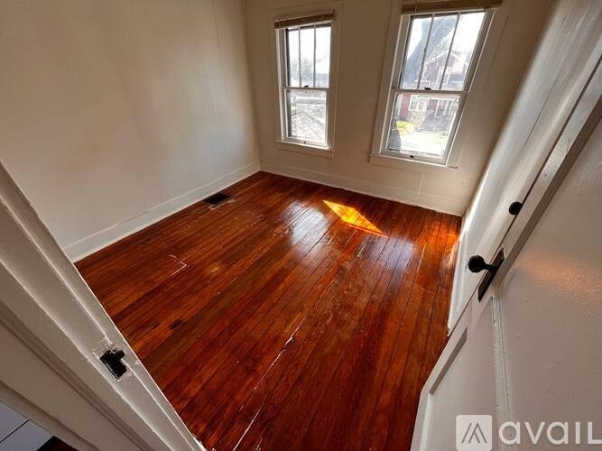 A room with wooden floors and two windows.