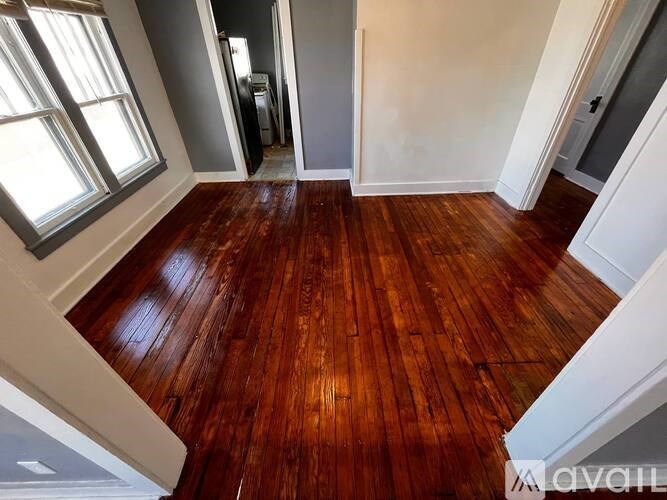 A room with wooden flooring and a window on the left side.