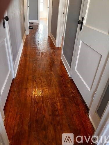A hallway with wood floors and white doors.