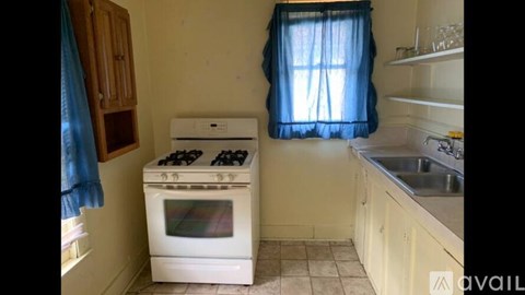 A kitchen with a white stove and a window with blue curtains.