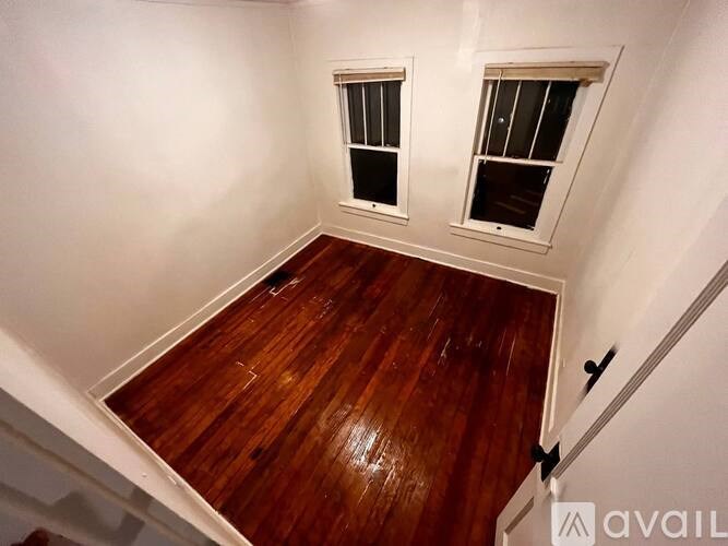 A room with wooden floors and two windows.