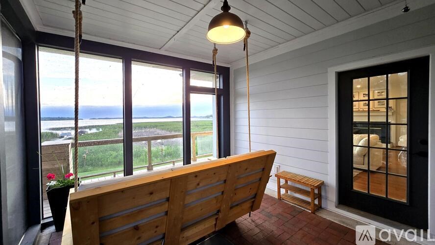 A wooden bench is placed in a room with a view of the ocean.