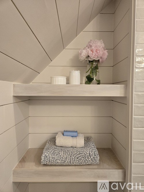 A small shelf with a towel, a book, and a vase with flowers.
