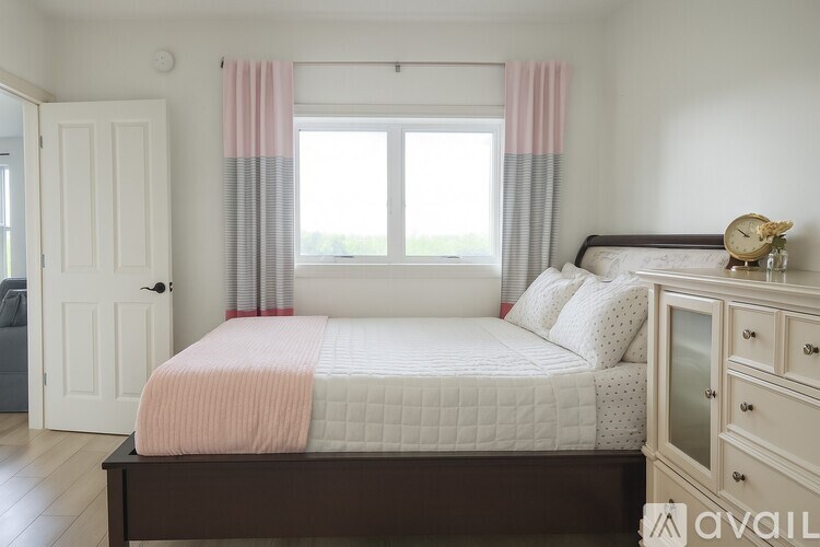 A bedroom with a bed, nightstand, and window with curtains.