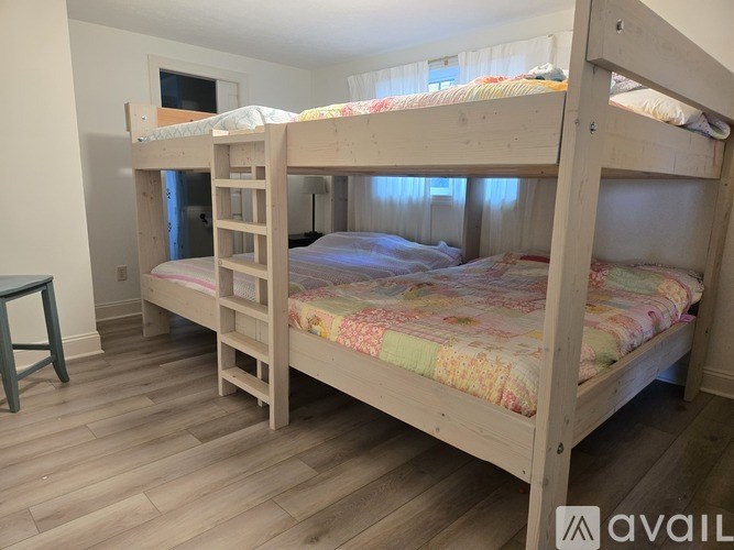 A room with wooden floors and two bunk beds.