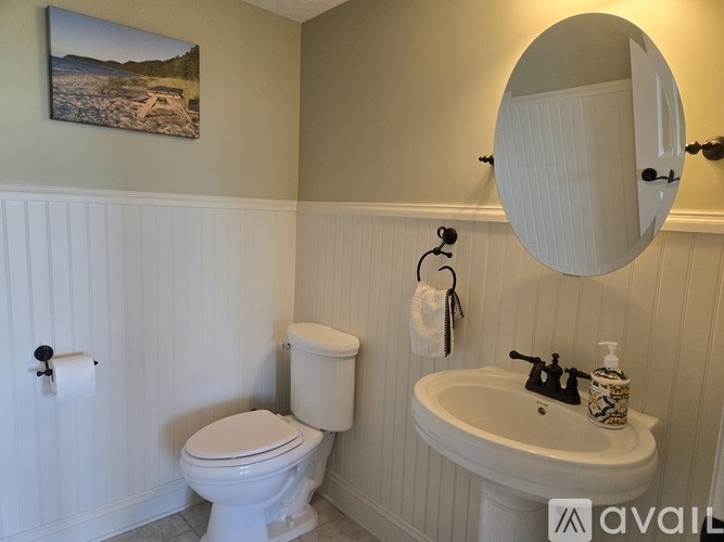 A bathroom with a toilet, sink, and a round mirror.