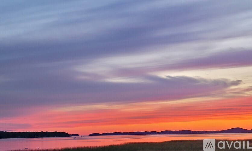 A beautiful sunset over a calm body of water with a reflection of the sky on the surface.