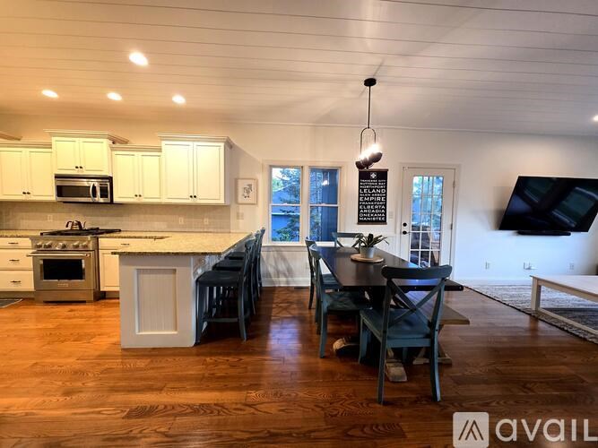 A kitchen with wooden floors and a dining table with chairs.