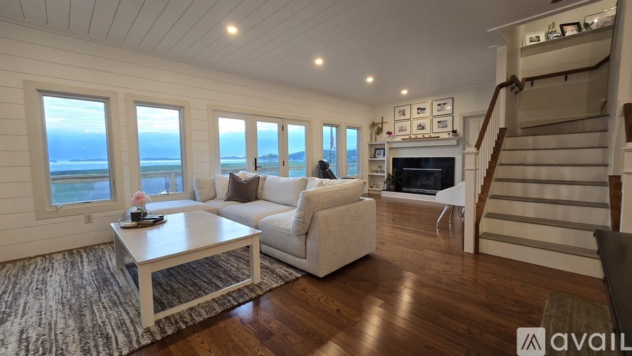 A living room with a couch, coffee table, and stairs leading to another room.