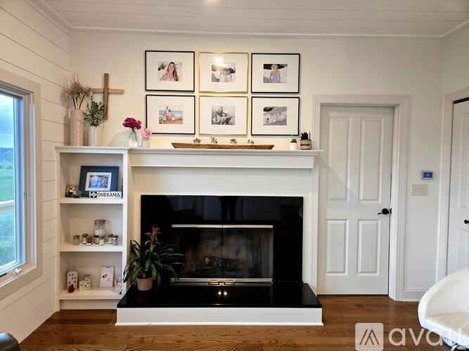 A white fireplace with a black mantle and a white chair in front of it.