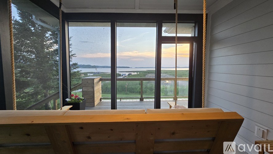 A wooden bench is in front of a window with a view of the water.