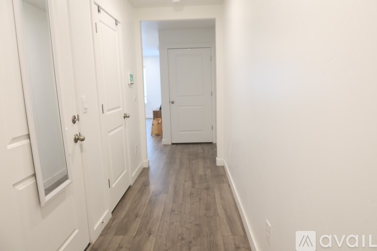 A hallway with white doors and a wooden floor.
