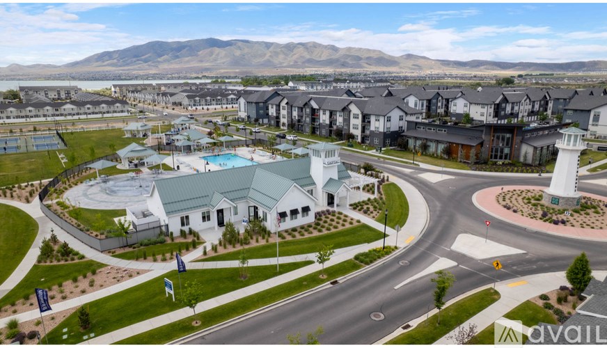 A large white building with a green roof is surrounded by a grassy area and a road with a roundabout.