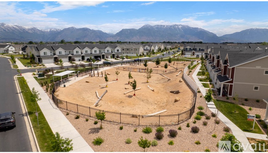 A playground with a fence and a car parked on the street.