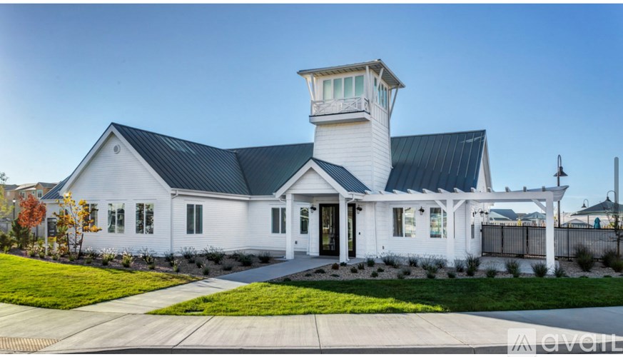 A white house with a black roof and a tower-like structure on the roof.