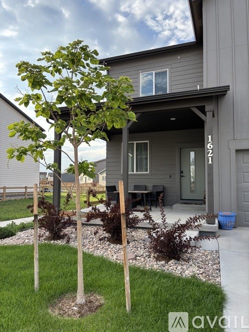A tree in front of a house with the number 1621 on it.
