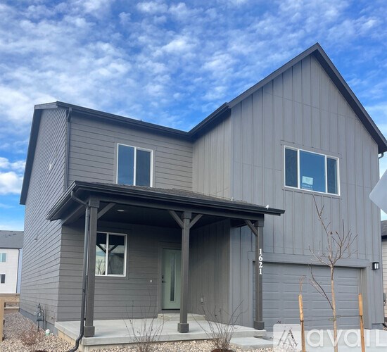 A grey house with a porch and a green door.