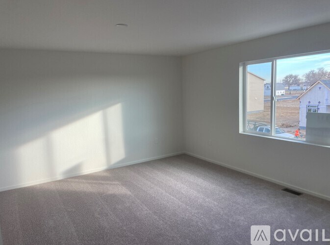 A room with a carpeted floor and a large window showing an outdoor view.