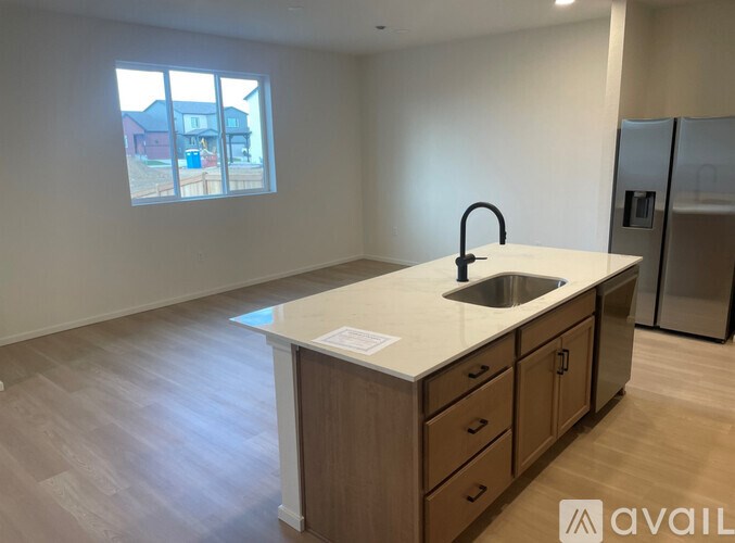 A kitchen with a sink and a window overlooking a residential area.