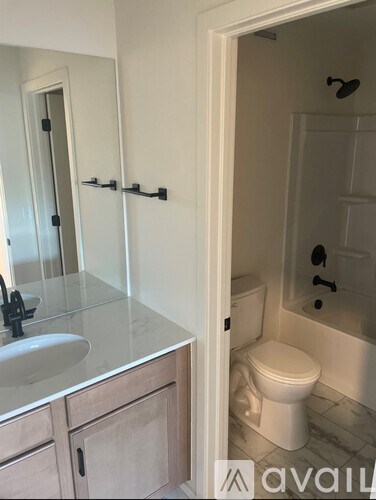 A white toilet is in a bathroom with a sink and a bathtub.