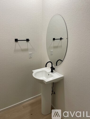 A white sink with a round mirror above it.