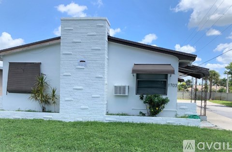 A white house with a chimney and a window with a brown awning.