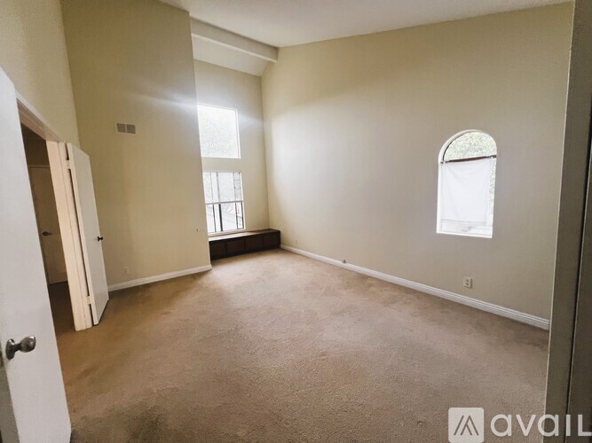 A room with a carpeted floor and a window with a white frame.