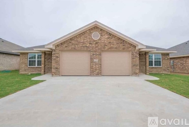 A two-car garage is attached to a brick house.