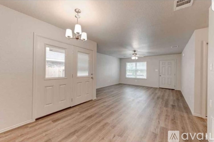 A room with wooden flooring and white walls, featuring a ceiling fan and a window with blinds.