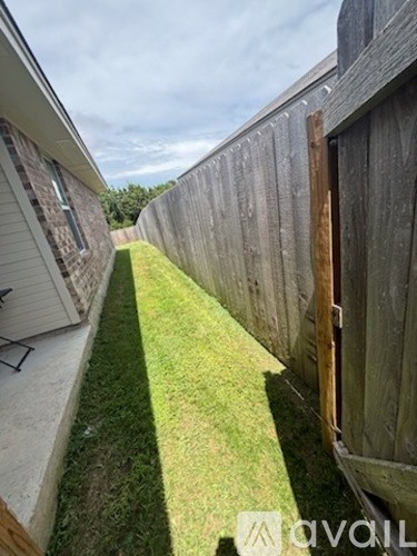 A narrow alley with a wooden fence and a grassy area.