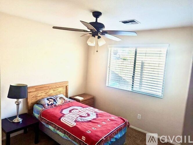 A bedroom with a bed, nightstand, and a ceiling fan.