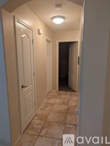 A hallway with tiled floors and white doors.