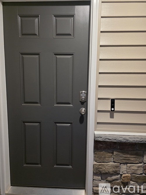 A grey door with a silver handle and a stone wall below it.