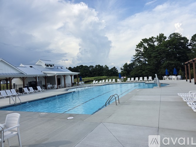 A pool with chairs around it and a building in the background.