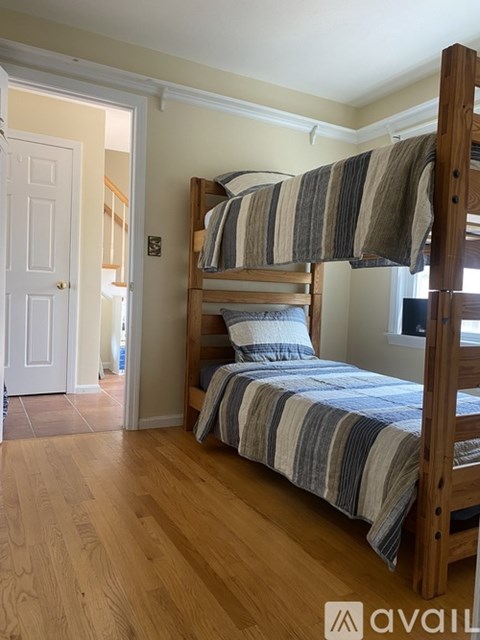 A bedroom with a bed and a wooden floor.